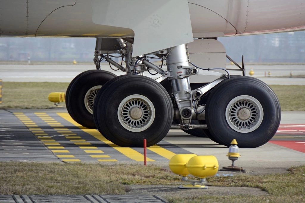 Close-up view of an airplane's landing gear, highlighting the chrome-plated metal alloy components used in the aerospace industry.