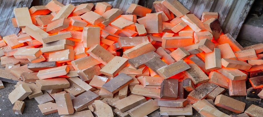 Red-hot refractory bricks made from chromite, cooling down after being used in a high-temperature industrial furnace.
