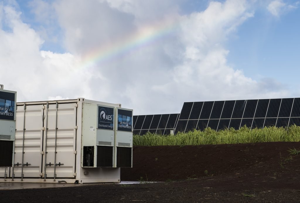 Solar farm with energy storage containers powered by lead-acid batteries under a rainbow.