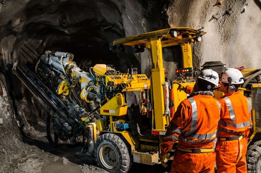 Workers operating a 5G-enabled autonomous drilling machine in an underground mine