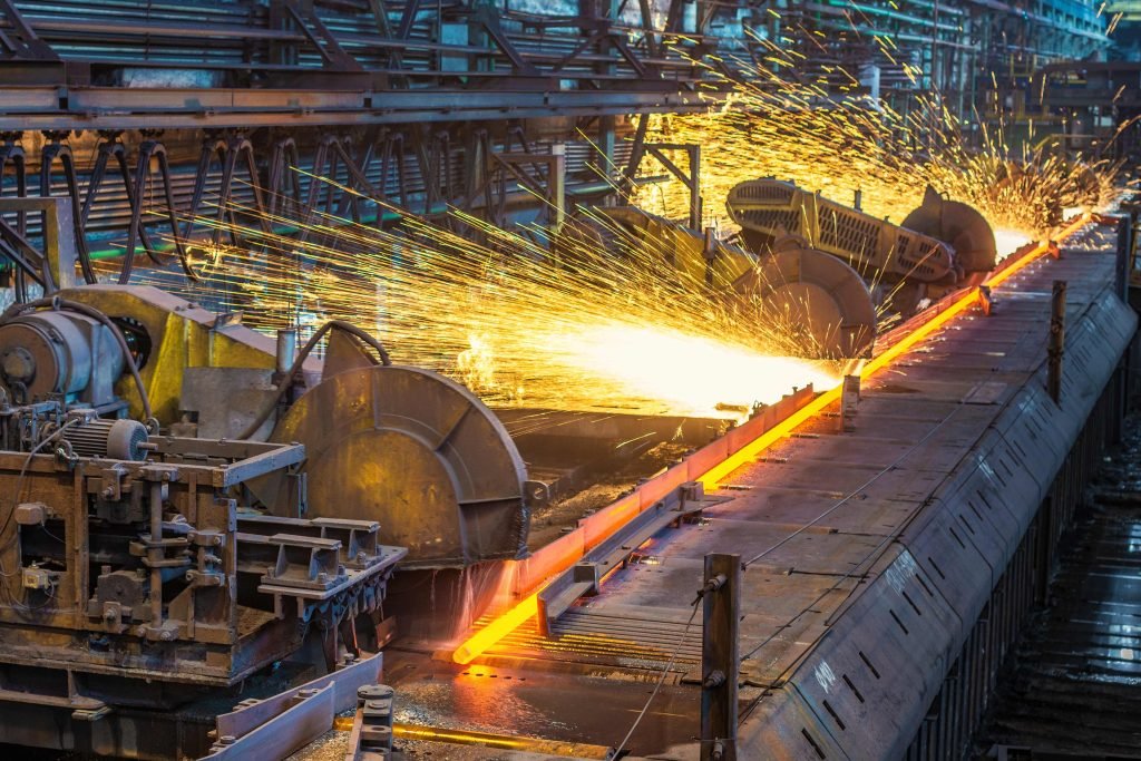 Molten metal being processed on a manufacturing line with sparks flying during the steel production process.